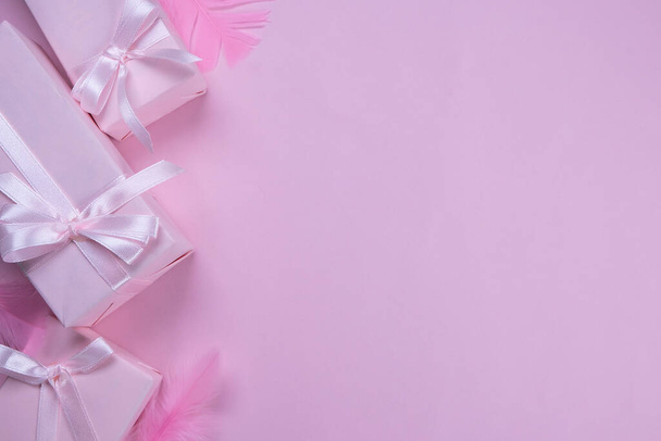 background with pink gift boxes with pink bows on a pink background with a place to insert text, copy space, decorated with feathers, top view, the concept of celebrating a girls birthday, party - Photo, Image