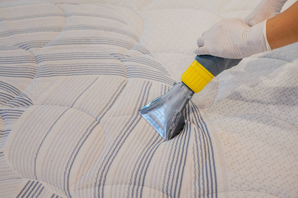 Trabajador Limpieza de una cama con aspiradora Método de extracción. - Foto, imagen