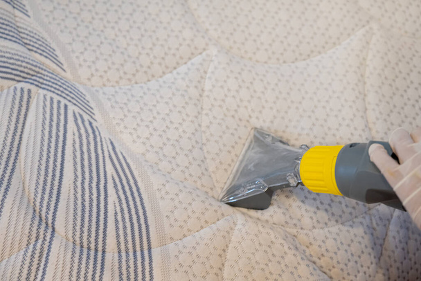 Trabajador Limpieza de una cama con aspiradora Método de extracción. - Foto, imagen