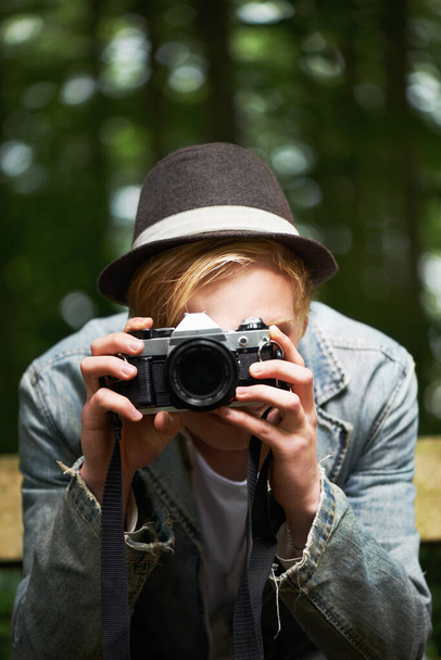 Portrait in a portrait. Closeup portrait of a young man taking pictures with a vintage camera in the forest - Photo, Image