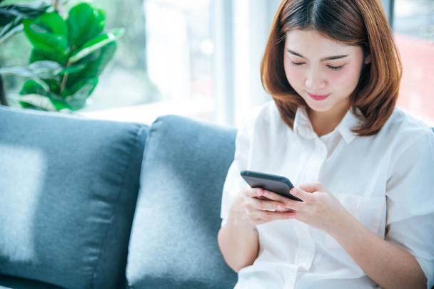 Asian woman holding smartphone with E-commerce Shopping online website Reading Online Article, Blog, vlog. Young Woman hands holding phone technology lifestyle. Happy Woman using digital smart phone - 写真・画像