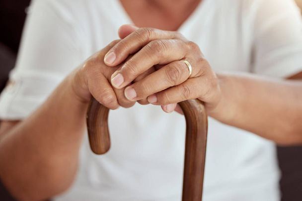 Hands of an elderly woman on a walking cane in a disability nursing or retirement home. Closeup of a disabled senior lady sitting with her stick at a wellness, healthcare or physical therapy center - Photo, image