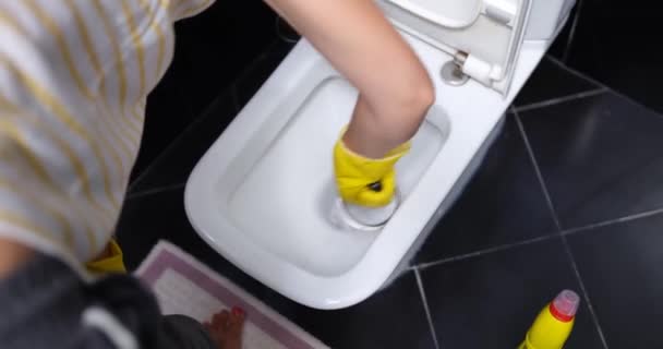 Руки в перчатках с помощью щетки для чистки унитаза в ванной комнате. Сантехника и услуги по уборке - Кадры, видео