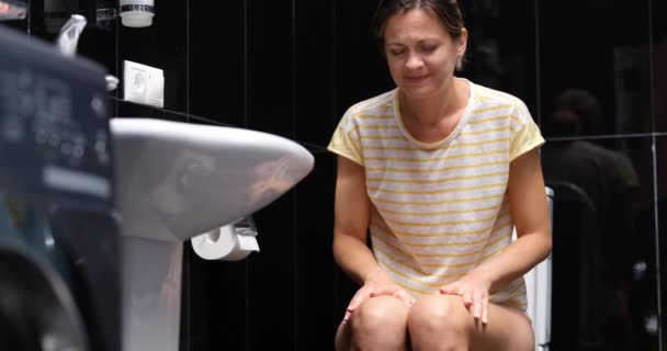 Ongezonde zieke vrouw die lijdt aan diarree, constipatie en buikpijn in het toilet. Behandeling van buikpijn en voedselvergiftiging - Video