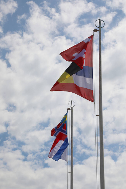 internationale Flaggen auf der Stange wehen während des Treffens zwischen den Vertretern verschiedener Nationen - Foto, Bild