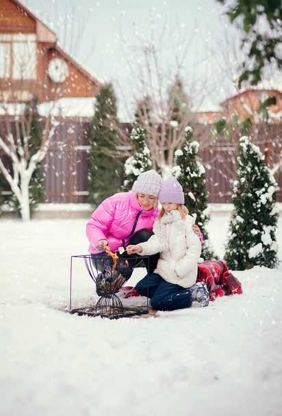 mom and daughter have fun in winter near the house. - Photo, Image