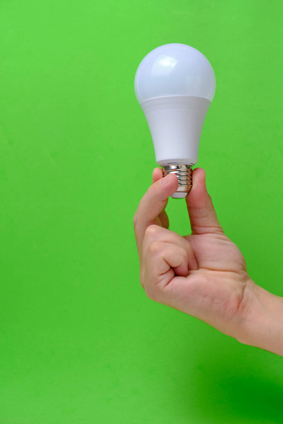 LED eco light bulb in hand on green background - Foto, afbeelding