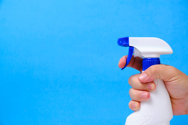 Sprayer for cleaning and washing windows, plumbing in hand blue background - Foto, Imagem