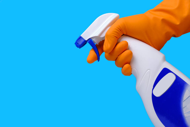 Pulverizador para limpar janelas e encanamento na mão com luva no fundo azul - Foto, Imagem