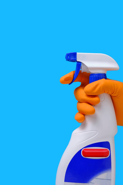 Sprayer for cleaning windows and plumbing in hand with glove on blue background - Photo, image