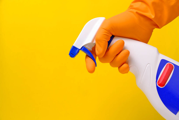 Sprayer for cleaning windows and plumbing in hand with glove on yellow background - 写真・画像