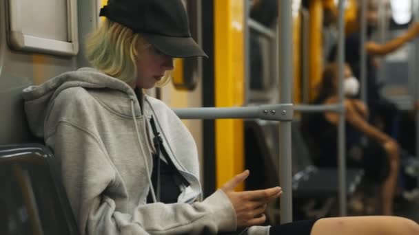 Teenage κορίτσι με βόλτες smartphone σε ένα τρένο του μετρό. - Πλάνα, βίντεο