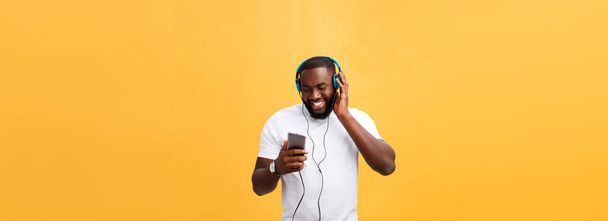 Αφρικανική αμερικανική άνθρωπος με ακουστικά ακούσετε και θα χορέψετε με τη μουσική. Απομονωμένα σε κίτρινο φόντο. - Φωτογραφία, εικόνα