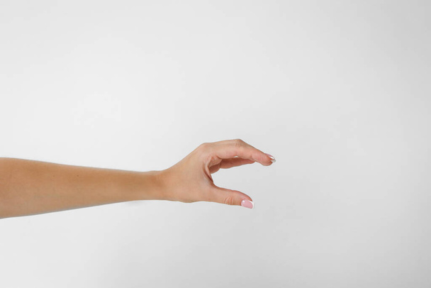 Рука жінки тримає два пальці, що показують розмір на білому тлі
 - Фото, зображення