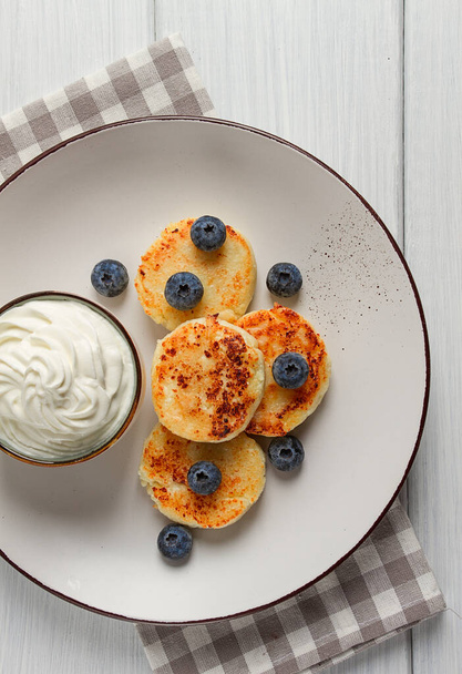 Cottage cheese pancakes , with blueberries ,breakfast , on a white wooden table, no people, top view, - Φωτογραφία, εικόνα
