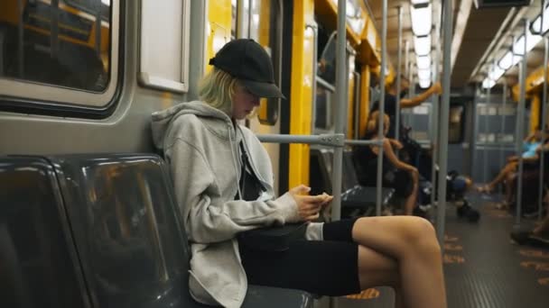 Adolescente avec smartphone monte dans un train de métro. - Séquence, vidéo