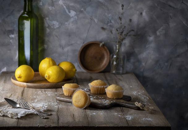 Κεκάκια λεμονιού και φρέσκα λεμόνια σε ξύλινο τραπέζι - Φωτογραφία, εικόνα