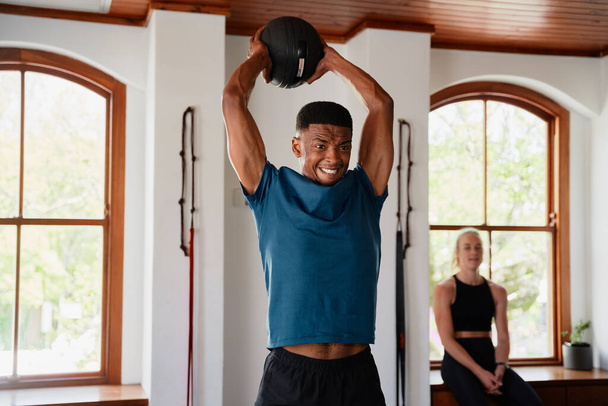 Young black man and caucasian woman in sportswear doing workout with medicine ball at the gym - Foto, Imagem