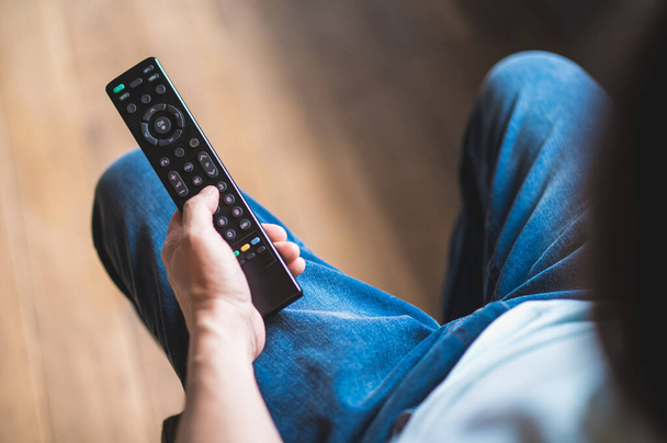 Watching tv. Man spending time at home and swithcing on tv with a tv remote - Foto, Imagen