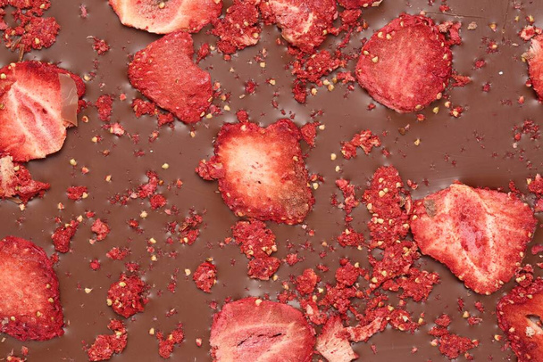 Chocolate bar with freeze dried strawberries as background, closeup - Фото, зображення