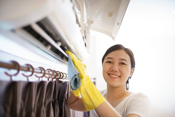 Mujer asiática limpiando un filtro de aire acondicionado sucio y polvoriento en su casa. Ama de casa quitando un filtro de aire acondicionado polvoriento. - Foto, imagen
