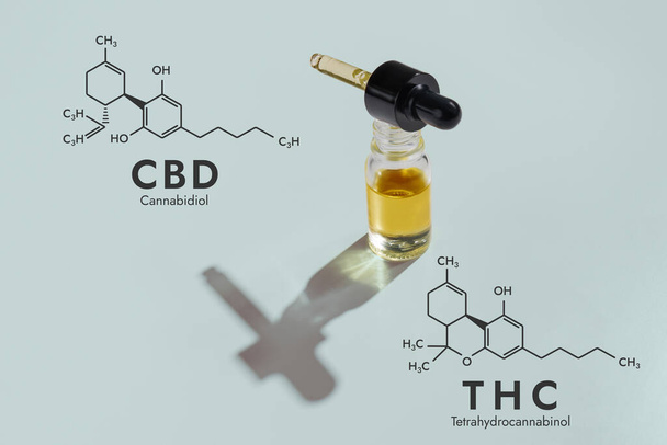 CBD oil in a clear, glass container with a dropper lid, isolated on a white background and biochemistry formula hexagon illustration, to represent the legalized marijuana extracts concept. - Photo, Image