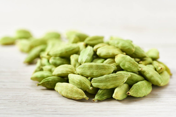 Pile green cardamom pods on a white wooden background, selective focus. - Photo, Image