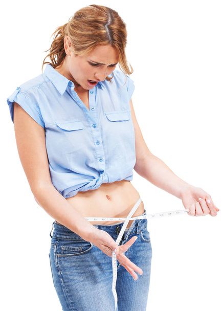 Gewichtsproblemen. schattig jong vrouw met een meten tape rond haar taille kijken aghast - Foto, afbeelding