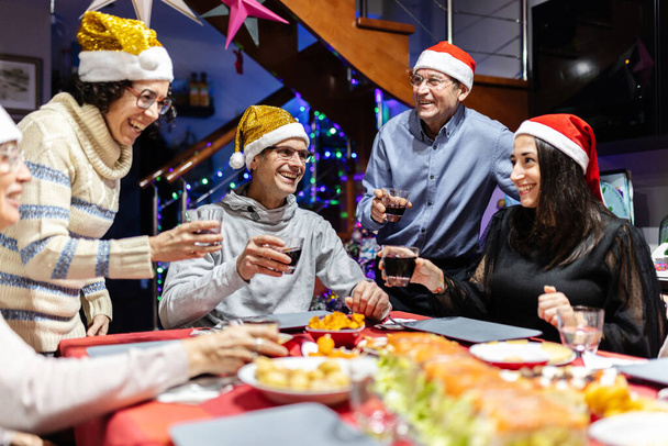Grupo de latinos latinos reunidos para la cena de año nuevo - Familia multigeneracional que celebra las fiestas de Navidad - Foto, imagen