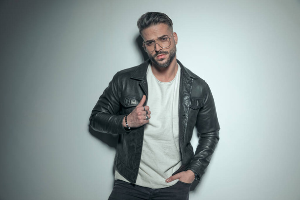 attractive casual man arranging his jacket and holding one hand in pocket with attitude in a fashion pose - Foto, immagini