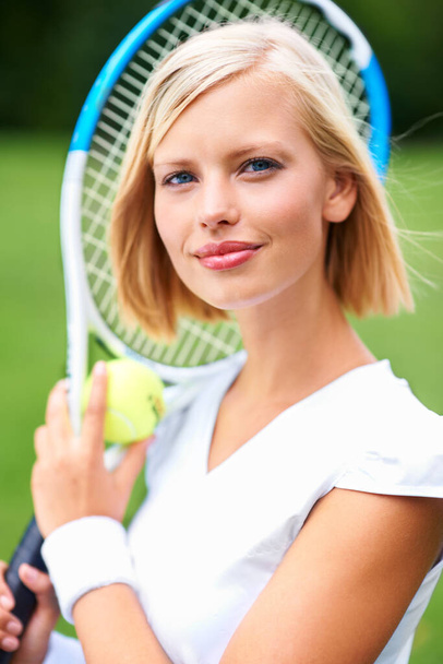 Připravuju se na výzvu. Portrét mladé tenistky držící míč a raketu - Fotografie, Obrázek