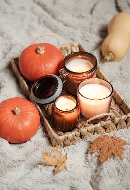 Fonott tálca gyertyákkal és sütőtökkel egy meleg takarón. Díszek az őszi ünnepekre az otthonnak. Hangulatos őszi koncepció. - Fotó, kép