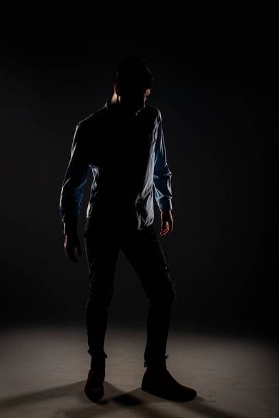 Hezký a dobře oblečený muž pózující před kamerou ve světlém ztlumeném pokoji - Fotografie, Obrázek