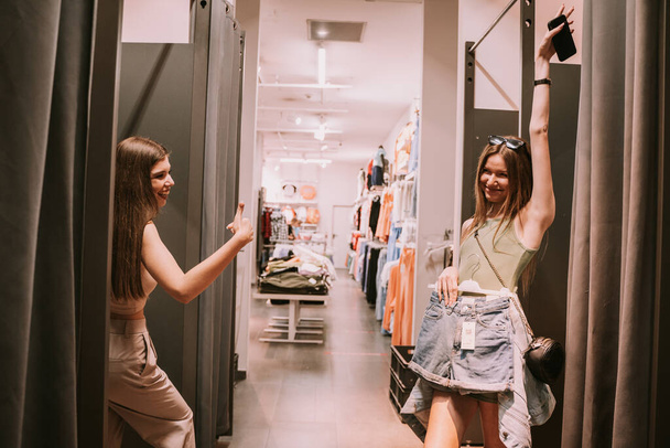 Két csinos lány szórakozik az öltözőben a boltban. - Fotó, kép