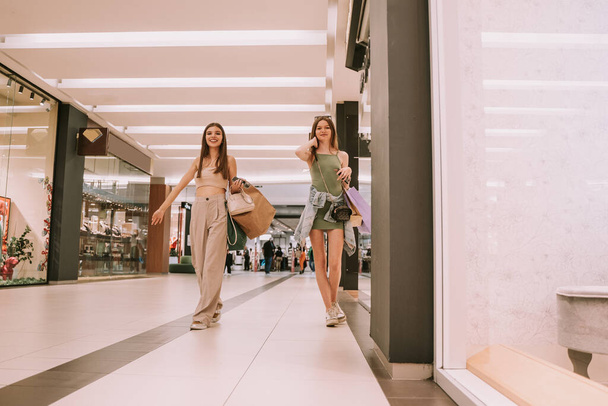 Δύο όμορφα κορίτσια περπατούν στο εμπορικό κέντρο. - Φωτογραφία, εικόνα