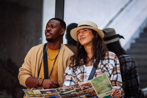 Un jeune couple multiracial regarde la carte pour un nouvel endroit à visiter - Photo, image