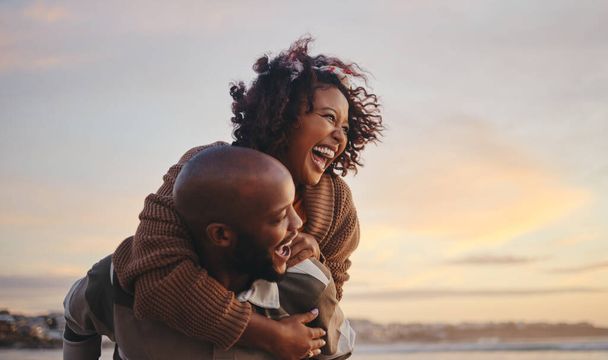 Black couple, travel and beach fun while laughing on sunset nature adventure and summer vacation or honeymoon with a piggy back ride. Comic, energy and black man and woman love on ocean holiday. - Foto, Imagen