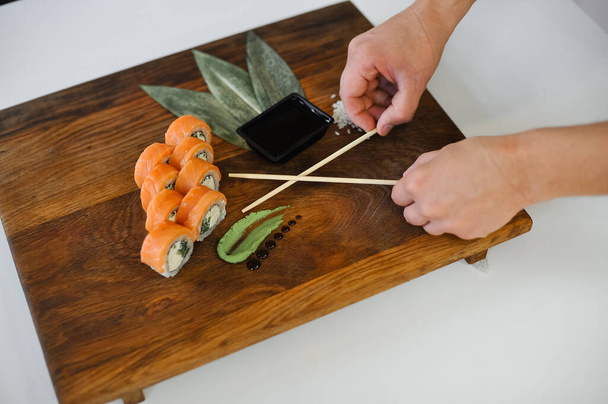primer plano de un chef cortando sushi con salmón y cuchillo - Foto, imagen