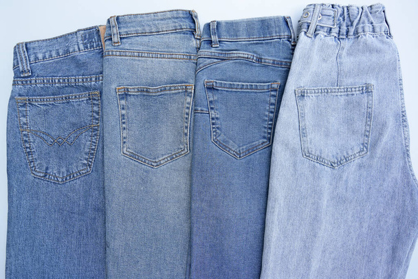 Lots of jeans pants in a stack. Denim background. The concept of buying, selling, shopping and trendy modern clothes. - 写真・画像