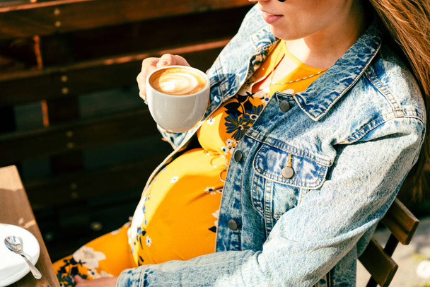 Πιες καφέ έγκυο γυναίκα. Ευτυχισμένο κορίτσι εγκυμοσύνης πίνουν ζεστό καφέ στο εστιατόριο. Αναπαράσταση πρωινού για ενέργεια και φρεσκάδα - Φωτογραφία, εικόνα