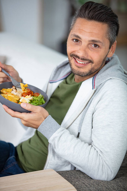 young man eating vegetarian salad with appetite - Zdjęcie, obraz