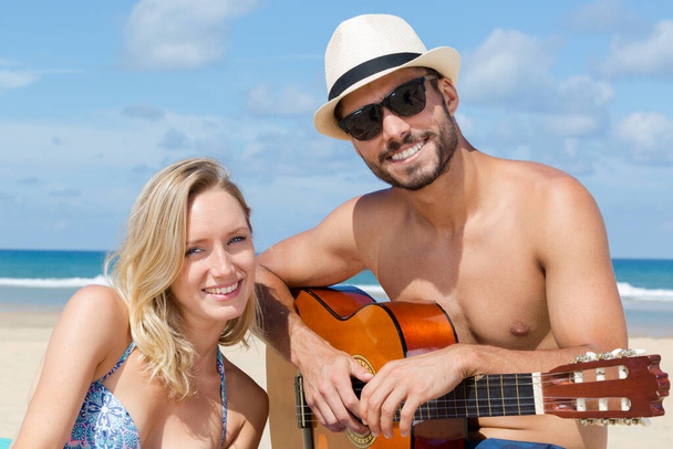 couple playing guitar on the beach - Photo, Image