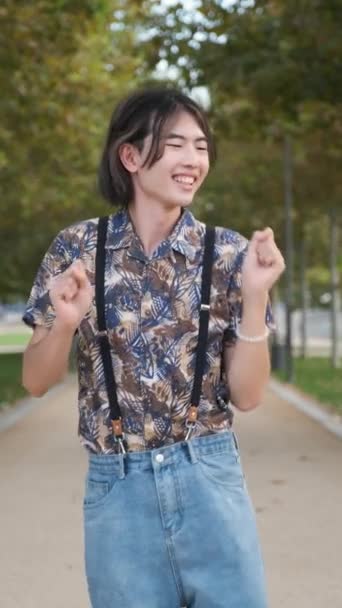 Mladý asijský muž s úsměvem a tanec rock and roll v parku. - Záběry, video