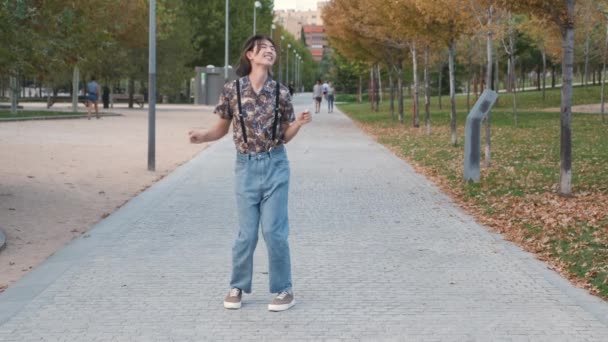Jonge Aziatische man glimlachen en dansen rock 'n roll in een park. - Video