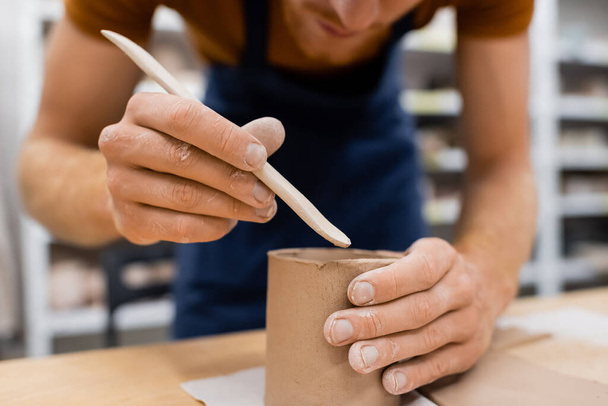 oříznutý pohled na koncentrovaného muže držícího tvar při modelování hliněného kelímku v keramické dílně - Fotografie, Obrázek