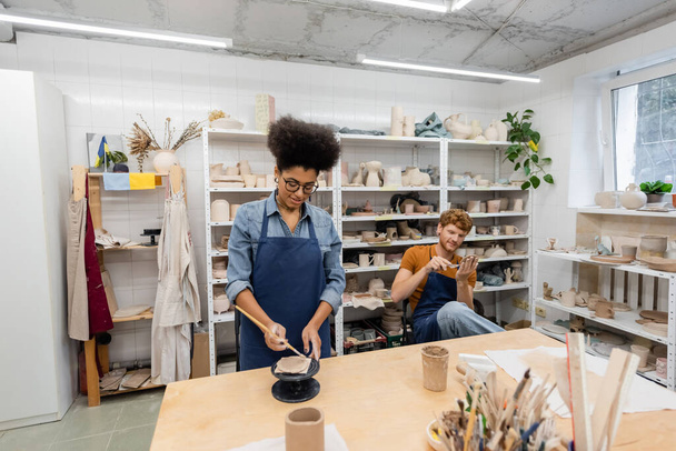veselý a různé rasy muž a žena v zástěrách ruční práce během hodiny keramiky  - Fotografie, Obrázek