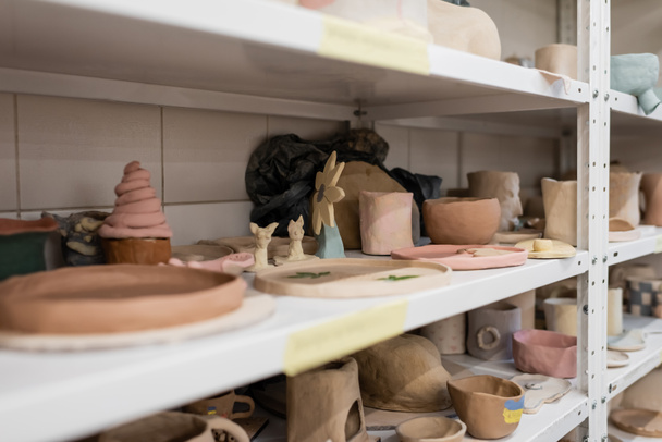 different clay sculptures on shelves of pottery shop  - Photo, Image