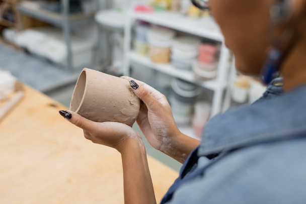 częściowy widok african amerykańskiej kobiety formowania filiżanki gliny w rękach - Zdjęcie, obraz