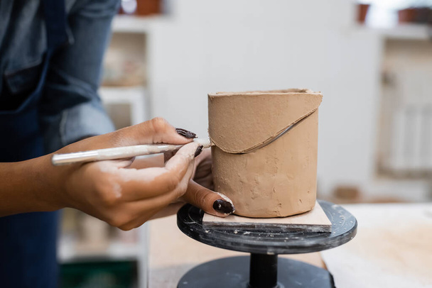 Vista recortada del escultor afroamericano cortando arcilla en taller de cerámica  - Foto, Imagen