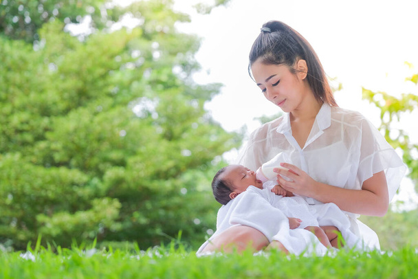 Beautiful breastfeeding mother, a family in an Asian garden - Photo, image